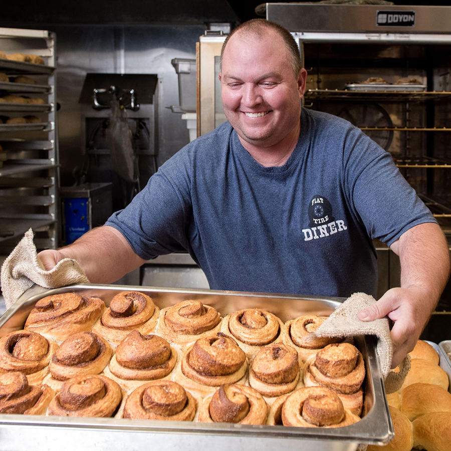 Chef Tom Mead taking fresh baked cinnamon rolls out of the oven.